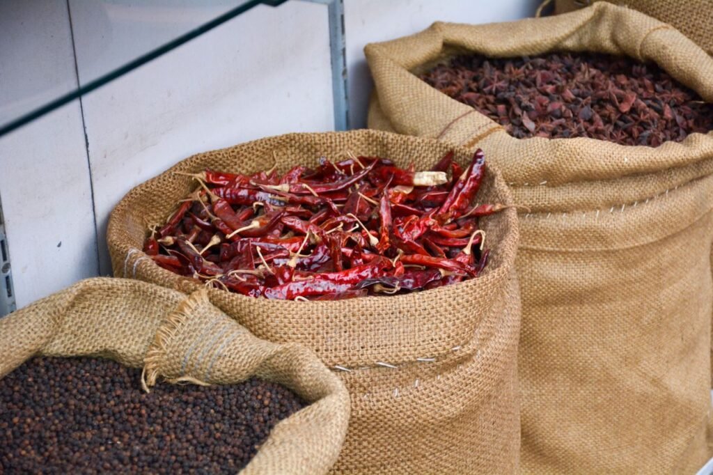 Burlap sacks filled with vibrant dried peppers and spices on display in a market.